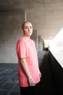 Seitenansicht einer Transgender-Person im T-Shirt, die tagsüber gegen Zaun in Mauerwerk blickt — Stockfoto
