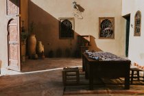 Mesa con mantel situada en el patio de mala calidad de la casa árabe tradicional en el día soleado en Marrakech, Marruecos - foto de stock