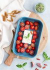 Top view of ripe cherry tomatoes with black olive slices and feta cheese in baking dish near uncooked penne — Stock Photo