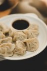 From above composition of steamed and roasted dumplings on white ceramic plate with soy sauce — Stock Photo