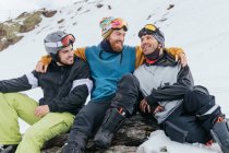 Fröhliche männliche Athleten in Schutzbrillen umarmen sich auf rauem Berg mit Schnee in der Provinz Granada Spanien — Stockfoto