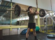 Focado Asiático atleta masculino fazendo deadlift com barra pesada durante o treino no ginásio — Fotografia de Stock