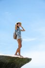Hermosa chica asiática de pie sobre las rocas, disfrutando de la playa en el soleado día de verano - foto de stock