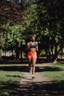 Young fitness African American woman running and making exercise on park — Stock Photo