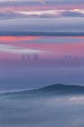 Vista aérea dos arranha-céus modernos de Cuatro Torres em madrid e montanhas cobertas com nuvens de carrapato sob o céu colorido durante o nascer do sol — Fotografia de Stock