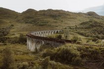 Vecchio binario ferroviario lungo l'antico ponte ad arco vicino a rough Hill nella giornata grigia a Glenfinnan, nella campagna britannica — Foto stock