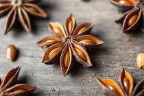 Крупный план ароматических сушеных анисовых звезд с семенами, разбросанными по деревенскому деревянному столу для гастрономии — стоковое фото