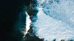 Drone view of abstract background of foamy sea waves of turquoise color rolling over seashore — Stock Photo