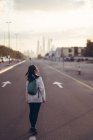 Back view of traveler woman walking down an avenue with Dubai Marina in the background — Stock Photo
