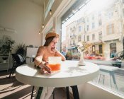 Mulher francesa na boina sentada à mesa no café com um copo aromático de café e croissant recém-assado — Fotografia de Stock