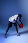 Mulher negra com roupa de basquete no estúdio usando géis de cor e luzes do projetor — Fotografia de Stock