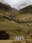 Weißes Haus in der Nähe von grasbewachsenen Hang des Hügels an bewölkten Tag in der Natur Großbritanniens — Stockfoto