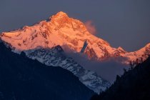 Rocky Himalayas mountains covered with snow lit by bright orange sundown light in Nepal — Stock Photo