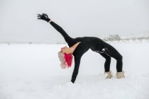Вид изящной женщины, практикующей йогу в Капотасане на снежном поле зимой — стоковое фото