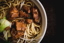 Tazón de fondo de deliciosa sopa de fideos asiáticos con costillas de cerdo colocadas en la mesa de café - foto de stock
