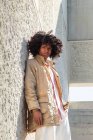 De baixo vista lateral afro-americano masculino em casaco vintage com penteado afro em pé nas escadas enquanto olha para a câmera — Fotografia de Stock