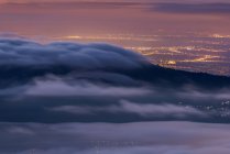 Vista aérea da cidade moderna de Madrid na Espanha e montanhas cobertas com nuvens de carrapatos sob o céu colorido durante o nascer do sol no Parque Nacional de Guadarrama — Fotografia de Stock