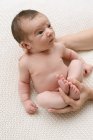 De cima de corte irreconhecível mãe amorosa olhando para adorável bebê nu na cama em casa — Fotografia de Stock