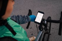 Зверху анонімний кур'єр вивчає маршрут на карті GPS перед їздою на велосипеді на міській вулиці — стокове фото