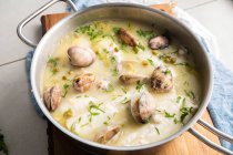 Сверху металлическая кастрюля с вкусным супом из морепродуктов с моллюсками и супом на деревянной доске на кухне — стоковое фото