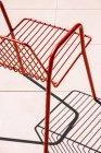 Літній відкритий червоний металевий стілець, розміщений на білій підлозі на сонячному світлі з тіні — стокове фото