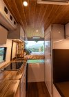 Modern interior of kitchen and bedroom in van parked on meadow in nature — Stock Photo
