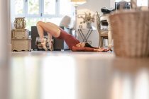 Ebenerdige Seitenansicht einer schlanken Balletttänzerin in Body und Spitzenschuhen, die zu Hause auf dem Boden liegt — Stockfoto