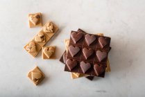 Vista dall'alto di deliziose caramelle al cioccolato con noci a forma di cuore sparse su sfondo bianco — Foto stock