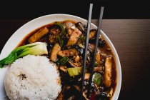 Vista aérea de la apetitosa berenjena Yuxiang cocida con verduras saludables y arroz en el plato blanco en el restaurante asiático - foto de stock