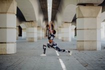 Young fitness African American woman stretching legs before running on city street — Stock Photo