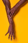 Crop view of anonymous muscular black man touching his forearm with hand on yellow background — Stock Photo