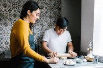 Любить этнических матерей и подростков с синдромом Дауна, готовящих тесто вместе на кухне дома — стоковое фото
