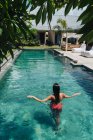 Вид ззаду анонімного туриста-жінки в купальнику, який плаває в рваному басейні під час літньої поїздки — стокове фото