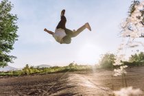 Akrobatische Männersprünge über dem Boden und gefährliche Parkour-Kunststücke an sonnigen Tagen — Stockfoto