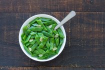 Desde arriba de ensalada saludable con judías verdes y rebanadas de ajo en un tazón servido en una mesa de madera - foto de stock