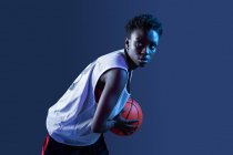 Femme noire avec tenue de basket-ball en studio à l'aide de gels de couleur et de projecteurs — Photo de stock