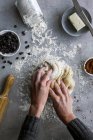 Сверху рука неузнаваемой женщины катит свежее тесто для выпечки на уютной кухне — стоковое фото