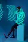 Schwarze Frau mit sportlichem Outfit im mit Gelen und Projektorlichtern beleuchteten Studio — Stockfoto