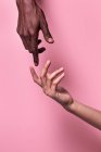 Противоположные руки афро-американского мужчины и белой женщины, указывающие друг на друга остроумным указательным пальцем изолированы на розовом фоне — стоковое фото