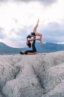 Side view of graceful woman balancing on legs of man during acroyoga session in mountains — Stock Photo