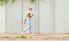 Вид збоку гей-чоловіка з рожевим волоссям та татуюваннями, що ходять по міській вулиці влітку — стокове фото
