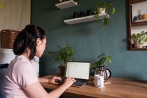 Азійська жінка-фрилансер читає документи на ноутбуці, сидячи за столом під час віддаленої роботи. — стокове фото