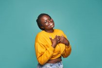 Веселая афроамериканка в модной желтой одежде счастливо танцует на синем фоне в студии — стоковое фото
