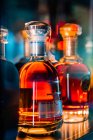 Durchsichtige Glasflaschen mit Whiskey, die nachts in der dunklen Bar auf dem Tresen stehen — Stockfoto