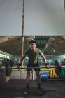 Konzentrierter asiatischer männlicher Athlet beim Kreuzheben mit schwerer Langhantel während des Trainings im Fitnessstudio vor laufender Kamera — Stockfoto