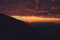Spectacular scenery of bright orange sun in evening sky over mountain range in Wales — Stock Photo
