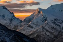 Rocky Himalayas mountains covered with snow with bright orange sundown light in Nepal — Stock Photo