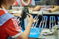 Dettaglio del lavoratore che applica la colla alla suola delle scarpe in una linea di produzione di fabbrica di scarpe cinesi — Foto stock