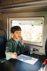 Petit garçon assis dans un camping-car tout en faisant ses devoirs et en regardant la caméra — Photo de stock
