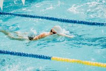 Вид сбоку паралимпийского спортсмена в очках и кепке без стиля ручного плавания в бассейне между дорожками — стоковое фото